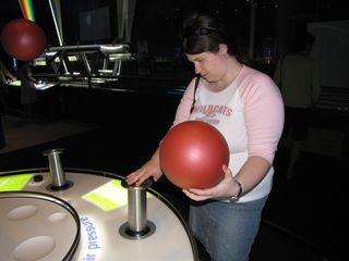 Sis explores how the floating ball device works. Normally, the ball that she is holding in her one hand hovers over the tube that she is touching with her other hand.