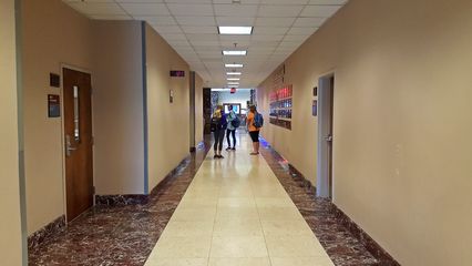 Prior to renovations, the first floor corridor in the classroom wing continued the marble theme from the lobby in the floors and the walls were a tan color, shown here in 2016.  Following renovations, the walls became white, and the floors were tiled.