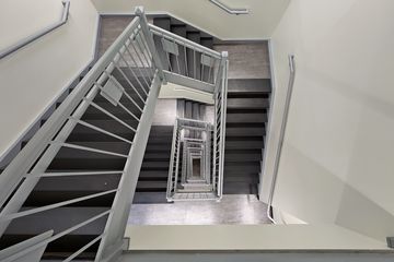 In 2022, the stairwell looks largely the same.  However, the flooring has been changed from rubber to tile, the lighting is different, and the railings and undersides of the stairs are now gray.