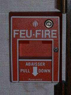 Two things you always take for granted - exit signs and fire alarms. In a country with two official languages (English and French), everything was bilingual. Thus "SORTIE" is added to an exit sign, and "FEU" is added to a fire alarm pull station.