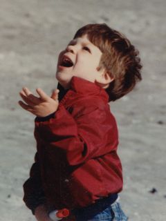 Here I am, quite amused, holding the string end of a bright orange kite on the beach one day.