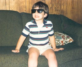 Having moved to Rogers, Arkansas by now, here I am sitting on the green couch demonstrating my complete lack of fashion sense. Note, though, the little alligator on the shirt.