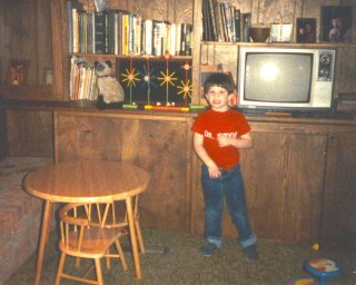 Here I am, wearing my red "Dr. Stop" shirt, showing off the fans I made out of Tinkertoys. I loved my Tinkertoys, and my favorite things to do with them for the longest time were to make fans like this, or spell "EXIT" with the "I" reaching way up to the ceiling.