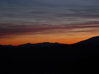 About three miles east of the motel buildings on Afton Mountain, at a scenic overlook on Interstate 64, the sun sets over a partly cloudy sky...