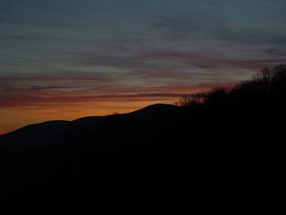 About three miles east of the motel buildings on Afton Mountain, at a scenic overlook on Interstate 64, the sun sets over a partly cloudy sky...