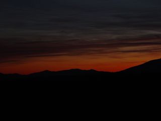 About three miles east of the motel buildings on Afton Mountain, at a scenic overlook on Interstate 64, the sun sets over a partly cloudy sky...