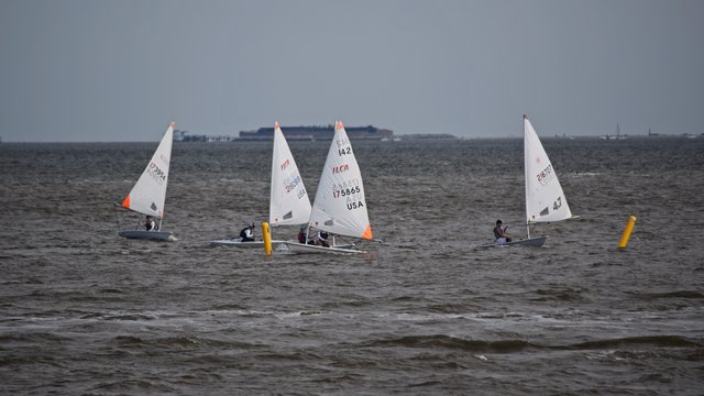 A group of people go dinghy sailing on the river.