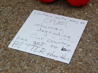 One participant placed a sign on the sidewalk in front of them, saying, "Certain acts may be cruel, inhuman, degrading... our country has got to be BETTER than this!"