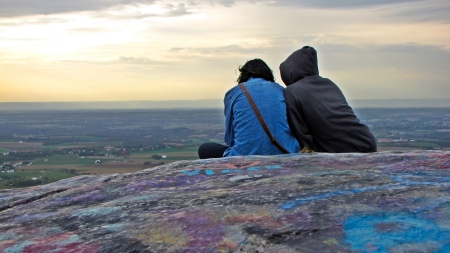 Two people sit on High Rock, looking down at a mobile device.