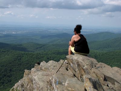 A woman sits at the summit of Humpback Rock