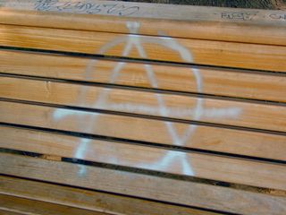 Four months after Inauguration Day, two benches still wore graffiti from the rally held in the park. One carries a penned message about George W. Bush, and the other carries a spray-painted anarchist symbol.
