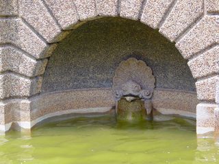 In niches on either side of the fountain, a figure stands watch.
