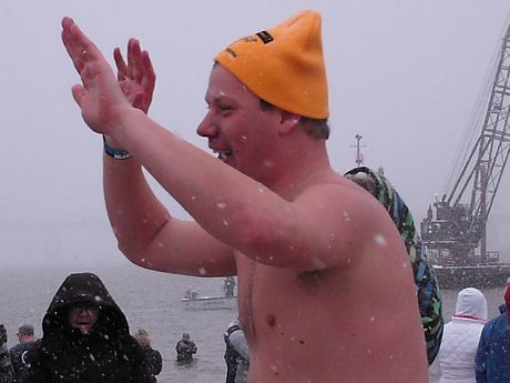A man gives high fives all around on his way down to the water to take the plunge.