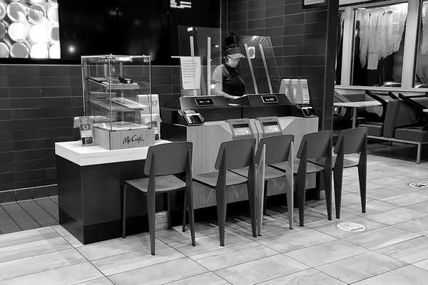 Social distancing setup utilizing chairs and plexiglass screens at the point of sale in a McDonald's restaurant in Colesville, Maryland.