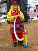 A man dressed in a clown costume makes balloon animals.