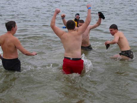A group of men dances around in the water.