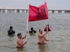 Two men stand in the water holding a banner for the Chloe's Cause Foundation, an organization to to raise awareness and help families with children with Leukemia and Down Syndrome.
