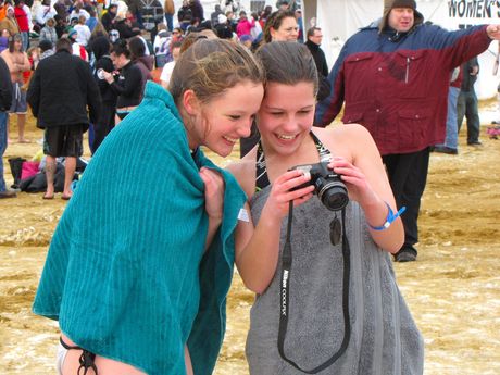 Two young women look at photos taken of them after emerging from the water.