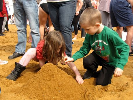 A boy and girl play in the sand on the beach.