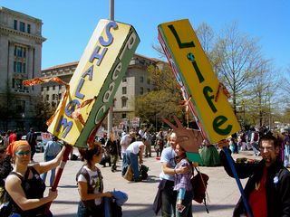 These two protesters made three-sided signs. The left sign said "Shalom", "Peace", and "Salaam", and the right sign said, "Life", "Peace", and "Hope".