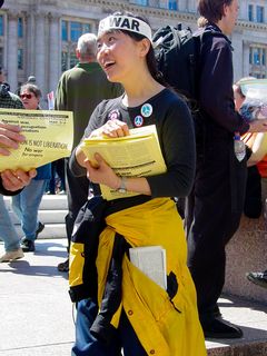 A woman with International A.N.S.W.E.R. hands out leaflets explaining both International A.N.S.W.E.R.'s position, as well as upcoming events.