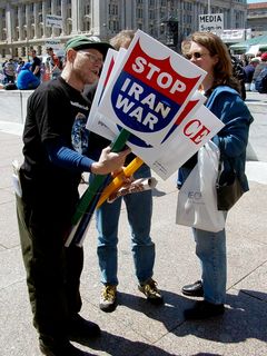 This protester distributes signs expressing some of the uncertainty at this protest, since Saddam Hussein's regime had unexpectedly fallen just before this protest went on. These signs, originally reading "STOP IRAQ WAR", now read "STOP IRAN WAR" after some quick cut-and-paste work. I observed several different kinds of modifications made to this style sign throughout the course of the day.