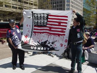 These two demonstrators portray the Navy as the ones with blood on their hands, with the flag's stars being replaced with skull-and-crossbones images.