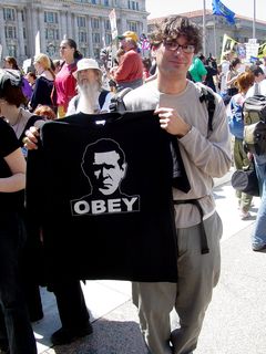 This gentleman holds up a black shirt showing Bush with the single command: OBEY.