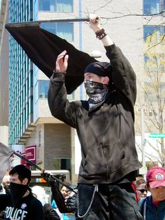 Quite a few black bloc protesters waved black and red flags, though black flags tended to predominate. This protester is waving his flag in front of cars on 14th Street.