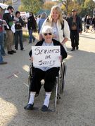 A woman in a wheelchair holds a sign reading, "Seniors for Sanity".