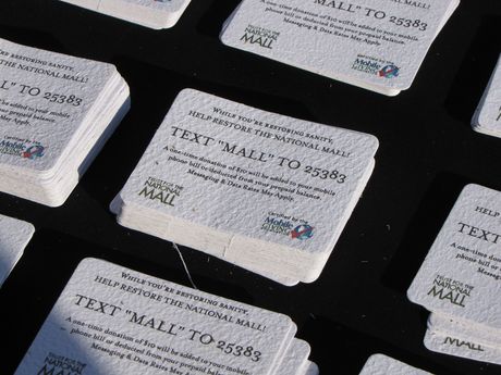 The Trust for the National Mall hands out cards encouraging people to make a donation by text message. In addition, the cards themselves are embedded with grass seeds, and thus if discarded on the ground and allowed to degrade naturally, would spread grass seed on the Mall.