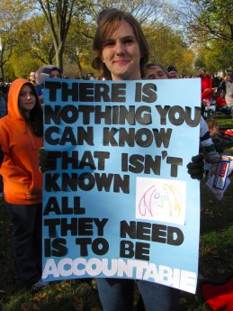 A person holds a sign advocating for accountability.