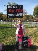 A woman holds a sign reading, "Beck! Go FOX yourself."