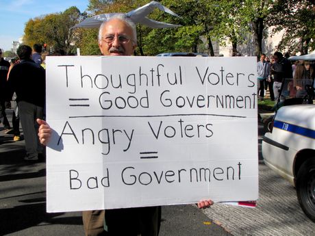 A man's sign compares the effect on government as caused by thoughtful voters versus angry voters.