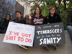 A group sits on a wall, holding signs about sanity.