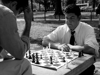Two gentlemen were involved in a chess game along one side of the circle, thinking carefully between each move.