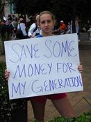A young woman holds a sign reading, "Save some money for my generation".