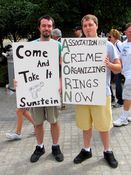 One man's poster refers to Cass Sunstein in a message about gun control, and another man's poster gives a new meaning to the acronym ACORN.