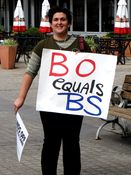 A woman holds a sign reading, "BO equals BS".