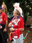 A woman wearing a pig hat places her hand over her heart while "The Star-Spangled Banner" is sung.