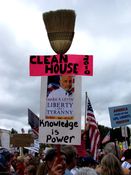 A man holds a sign mounted to a broom, symbolizing cleaning house in the 2010 midterm elections, and promoting one of right-wing pundit Mark Levin's books.