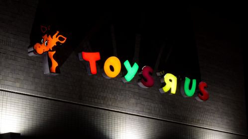 Sign on the back side of the former Toys "R" Us store in Gaithersburg, Maryland, still lit up approximately three months after the store closed along with the rest of the company.