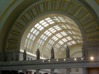 Inside the main atrium, we find barrel-vaulted ceilings decorated with 74 pounds of gold leaf, skylights, and statues ringing the space.