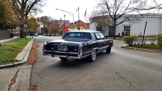 A Cadillac Brougham makes a left turn out of an alley onto North Oakley Avenue.