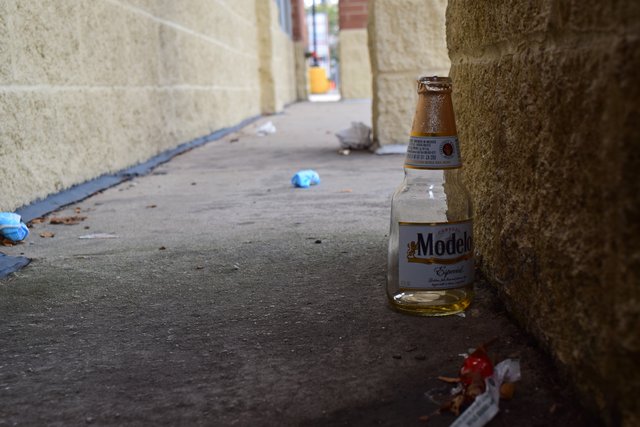 An empty beer bottle, amongst other discarded items, behind a column in front of 2301 West Lawrence Avenue.