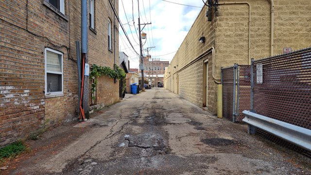 Alley west of North Oakley Avenue, running between a shopping center and a row of houses.  View facing west.