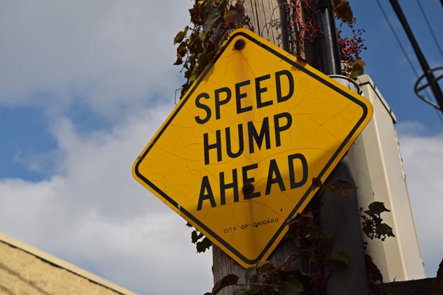 "SPEED HUMP AHEAD" sign attached to a utility pole.