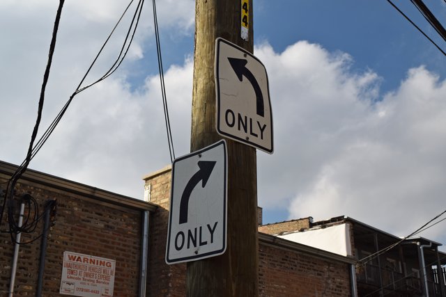 Signage at the point where the alley rounds a corner and changes direction from east-west to northwest-southeast.