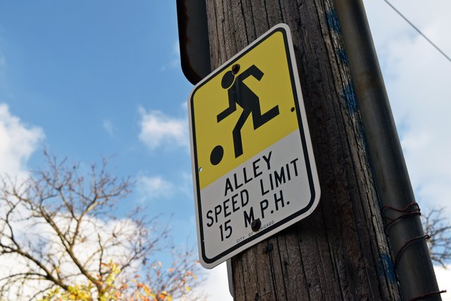 Alley speed limit sign, with a pictogram of a child playing with a ball.