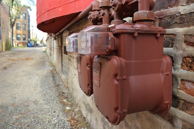 Gas meters on the side of a building on the alley side.